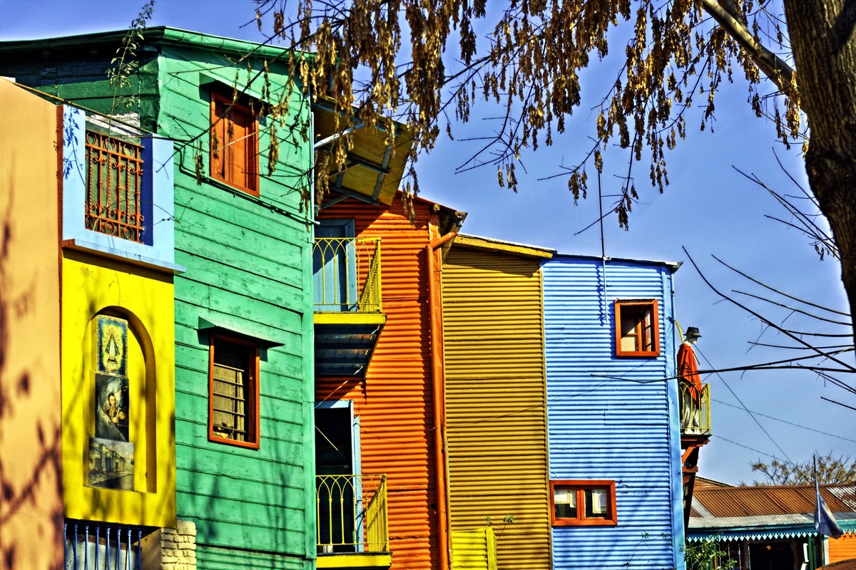 Tree-lined residential street with apartment balconies and corner shops in Buenos Aires